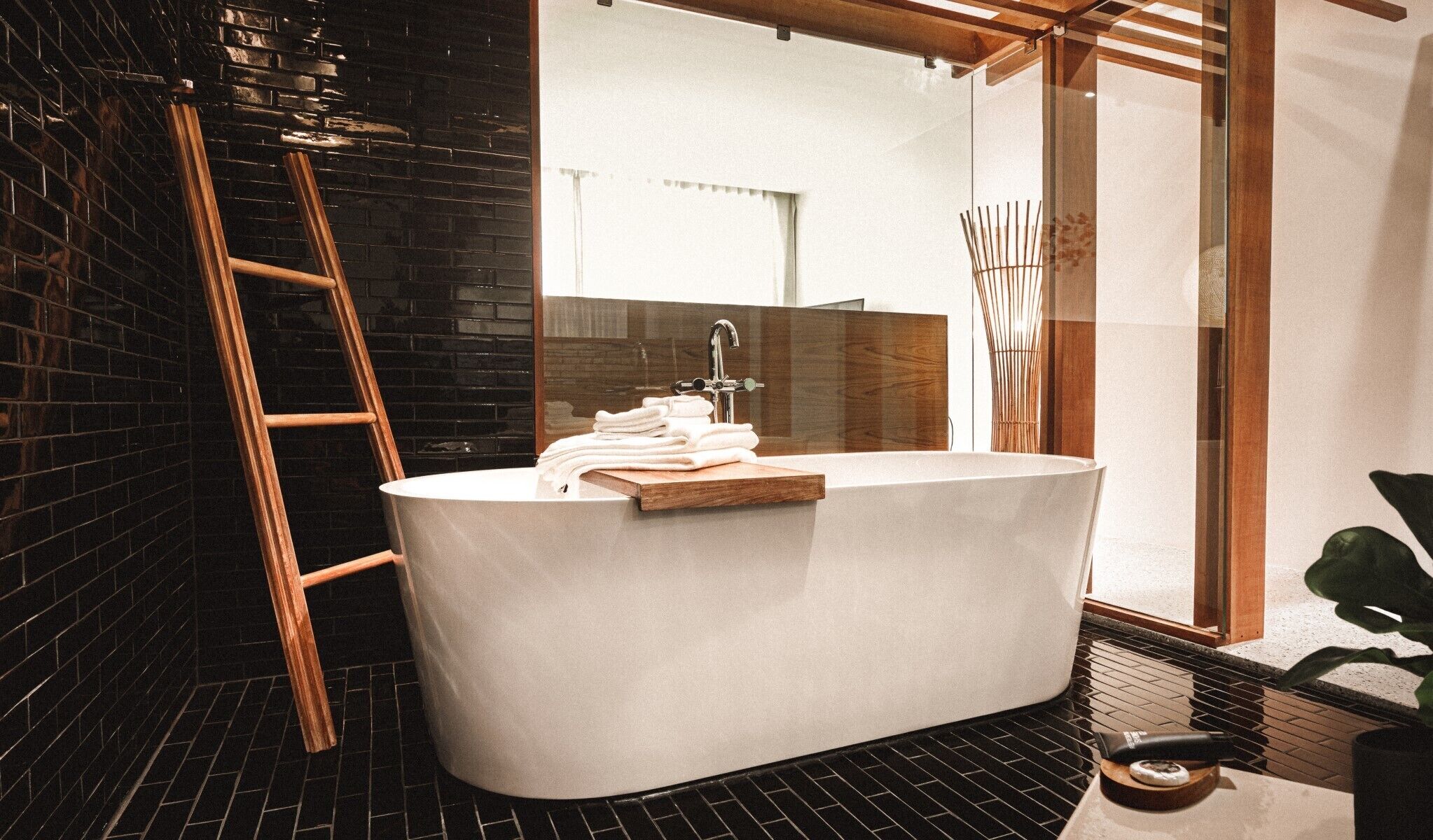 Un baño moderno con una bañera independiente, una escalera de madera y un espejo grande.