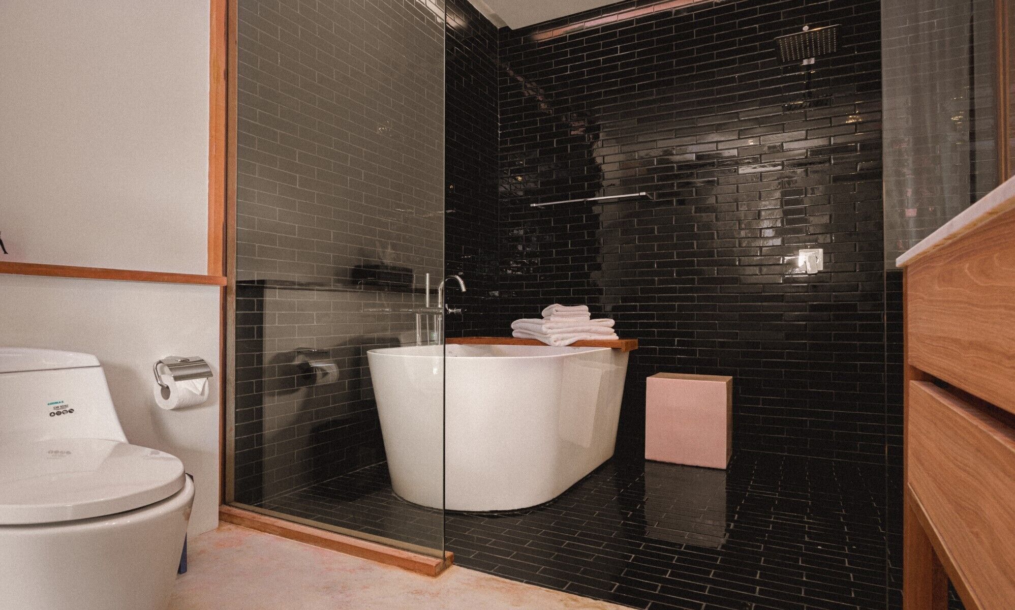Un baño moderno con una bañera blanca, ducha con cerramiento de vidrio y tocador de madera.