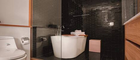 Un baño moderno con una bañera blanca, ducha con cerramiento de vidrio y tocador de madera.