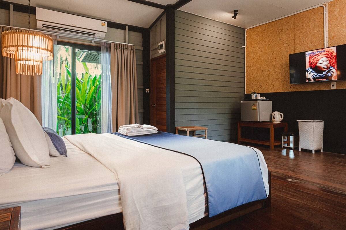 A hotel room with a bed, a TV mounted on the wall, a small table, and a chair.