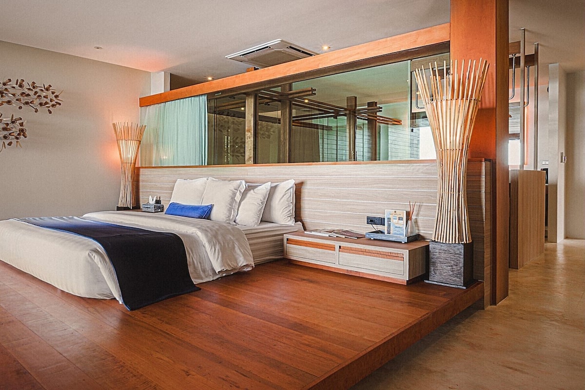 A modern bedroom with a large bed, a bedside table, and a built-in wardrobe.
