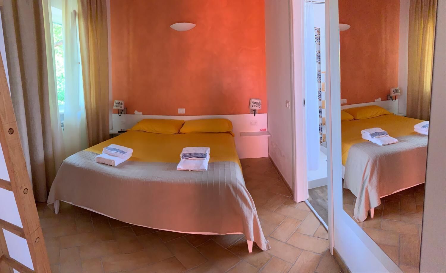 A room with two beds, each with a yellow headboard, a bedside table, and a mirror.