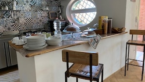A kitchen with a central island, a round window, and a view of the outside.