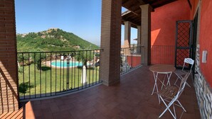 A balcony with a view of a swimming pool and a hill.