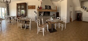 A spacious dining area with multiple tables and chairs, a fireplace, and a large wooden cabinet. - B&B I 4 Sentieri (Castel San Pietro Romano)