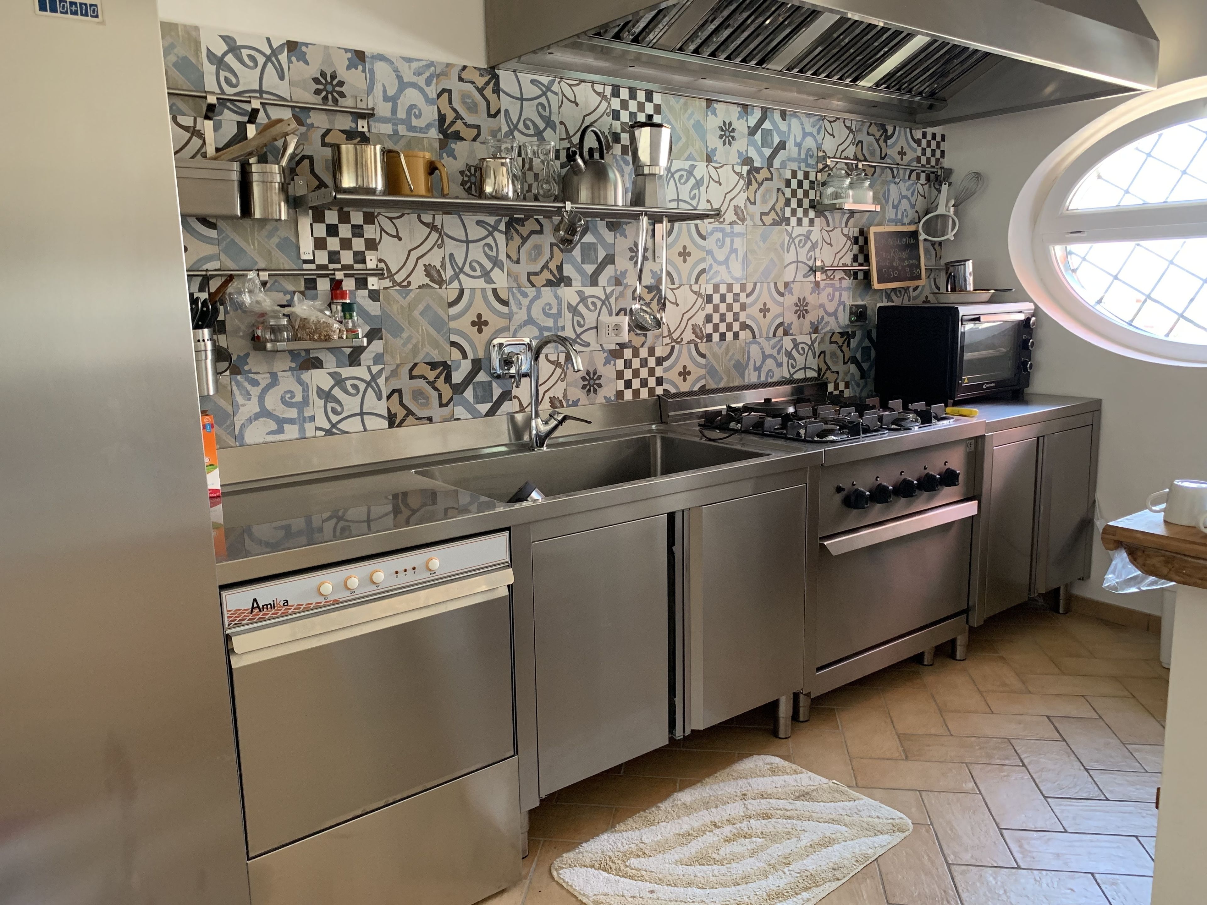 A modern kitchen with stainless steel appliances, a checkered backsplash, and a window providing natural light.