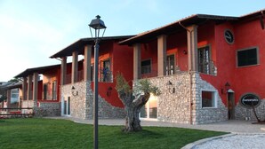 A red building with stone accents, multiple balconies, and a well-maintained lawn.