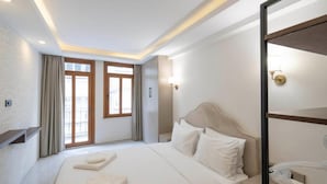 A hotel room with a large bed, a bedside table, a mirror, and a window with curtains. - Arach Hotel Harbiye (Istanbul)