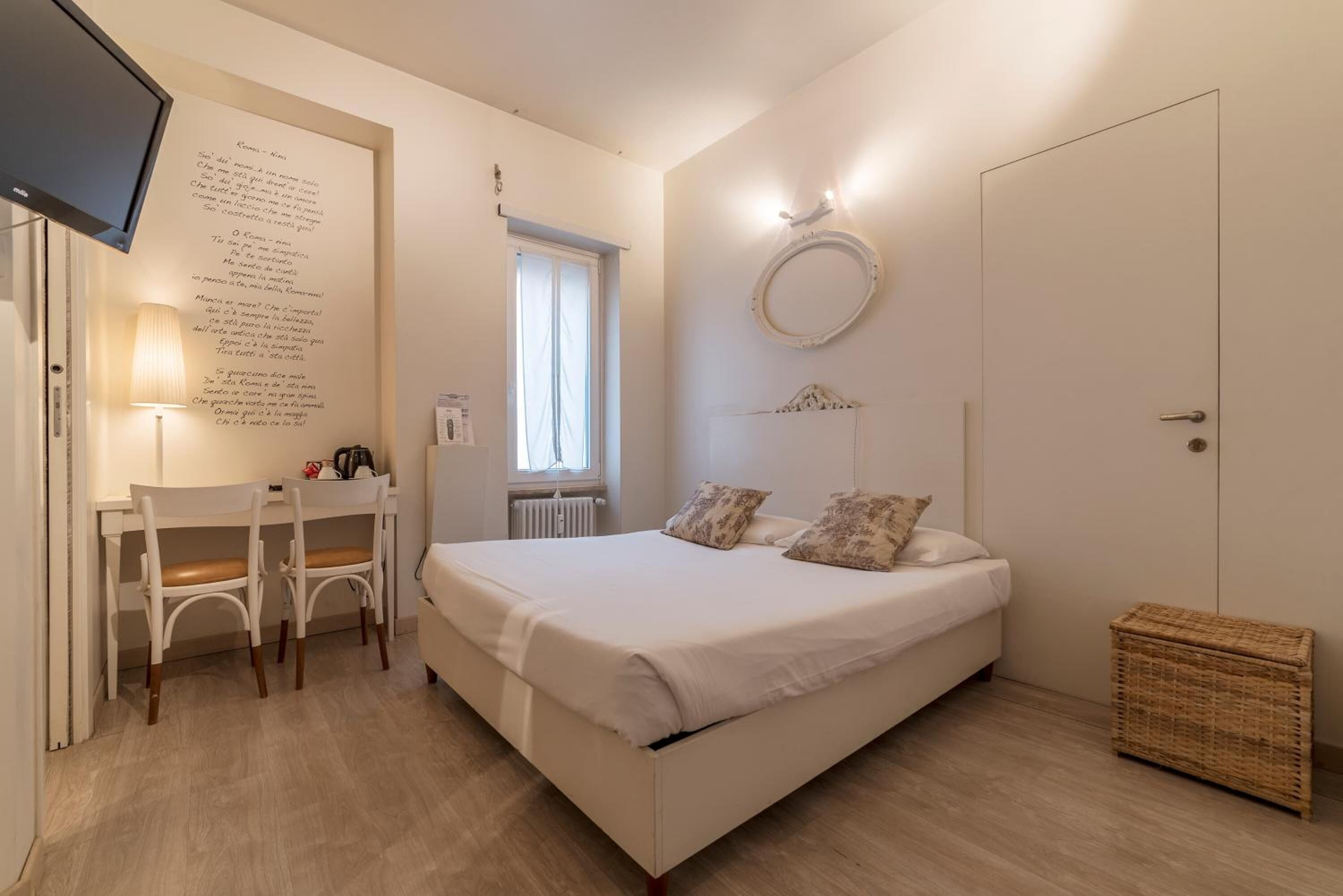 Una camera da letto con un letto, una scrivania con sedie, una TV e una finestra.