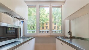 Eine moderne Küche mit großem Fenster, Edelstahlgeräten und weißen Schränken.