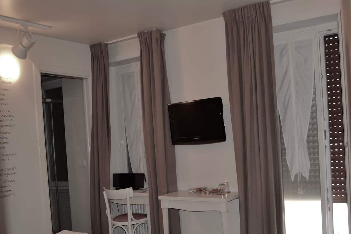A hotel room with a bed, a desk, a chair, a television, and a window with curtains.
