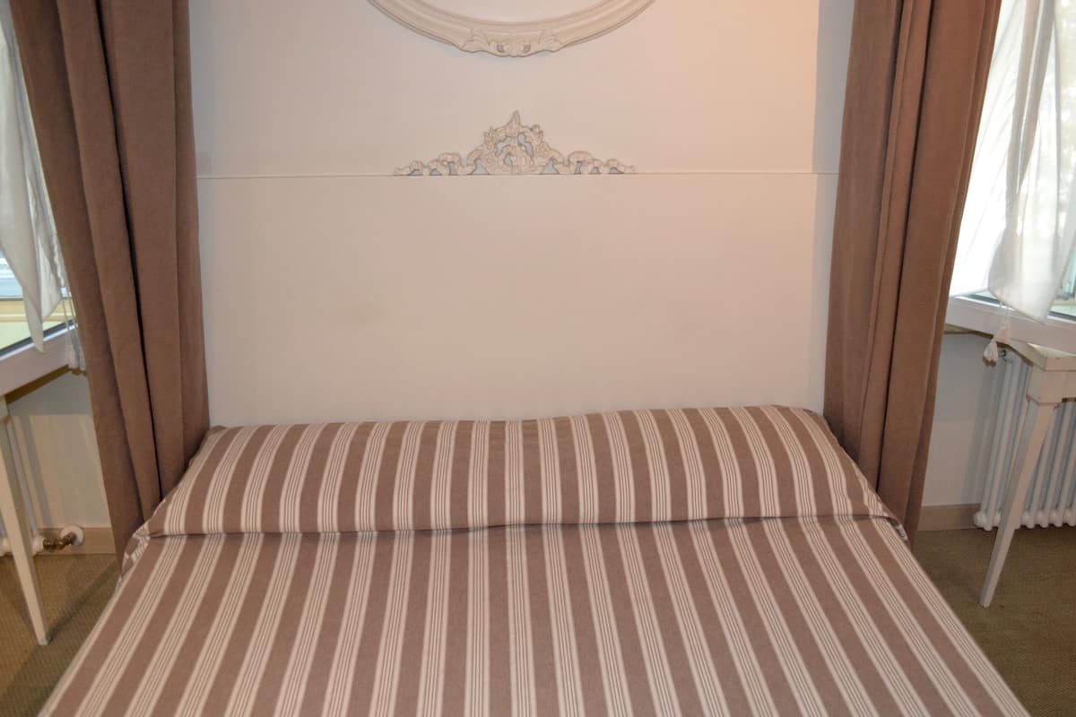 A bed with a striped bedspread, a decorative wall panel, and curtains on either side.