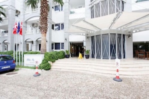 A hotel entrance with a white facade, multiple balconies, and a palm tree. - Blue Lagoon Otel (Marmaris)
