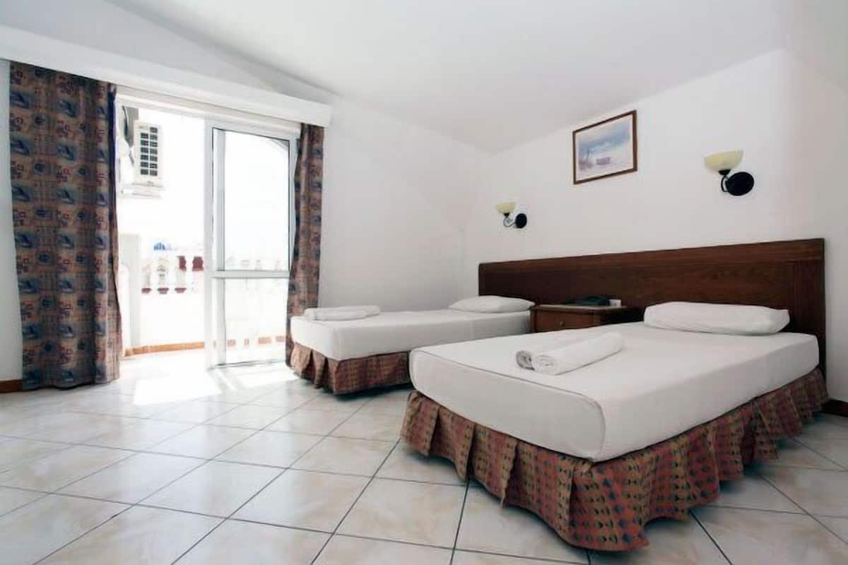 Habitación de hotel con dos camas, un ventanal grande y vistas al exterior.