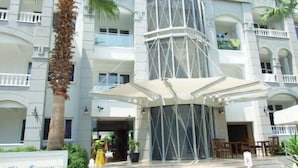 Entrada de hotel con una zona de estar al aire libre techada, palmeras y un letrero que dice "Blue Lagoon".