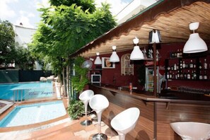 A poolside bar area with a wooden ceiling, white hanging lamps, and a bar stocked with bottles. - Blue Lagoon Otel (Marmaris)