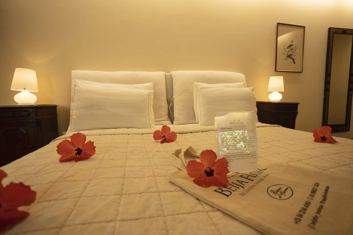 Une chambre d’hôtel avec un lit bien fait, deux lampes de chevet et un arrangement floral sur le lit.