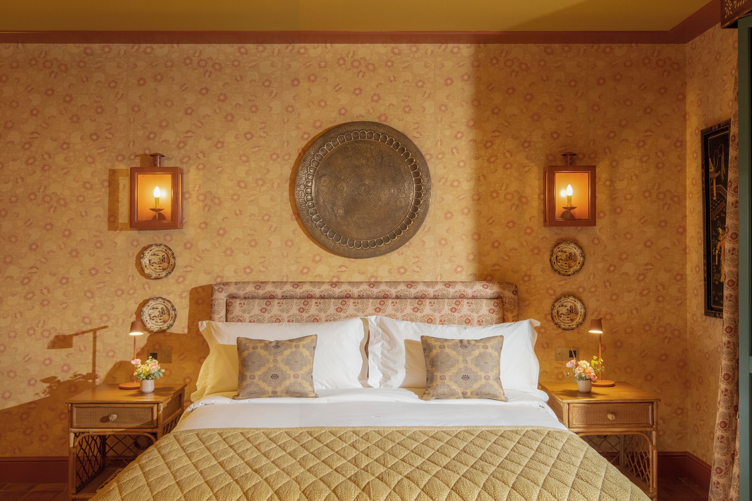 Ein Hotelzimmer mit einem großen Bett, zwei Nachttischen mit Lampen und einem dekorativen Spiegel an der Wand.