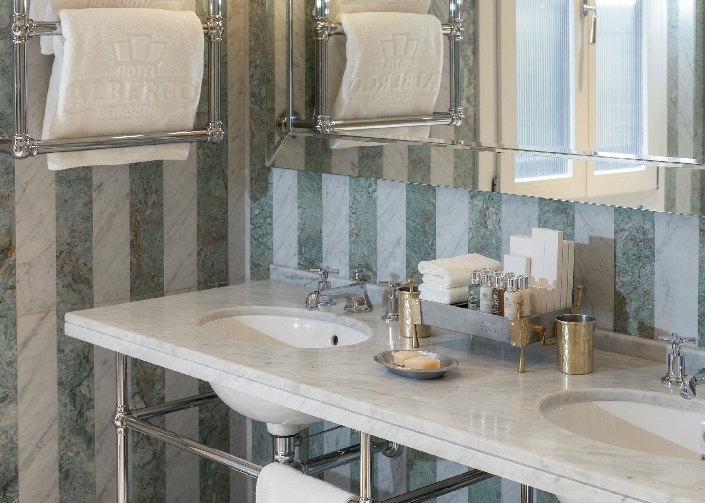 A bathroom with two sinks, a large mirror, and towel racks.