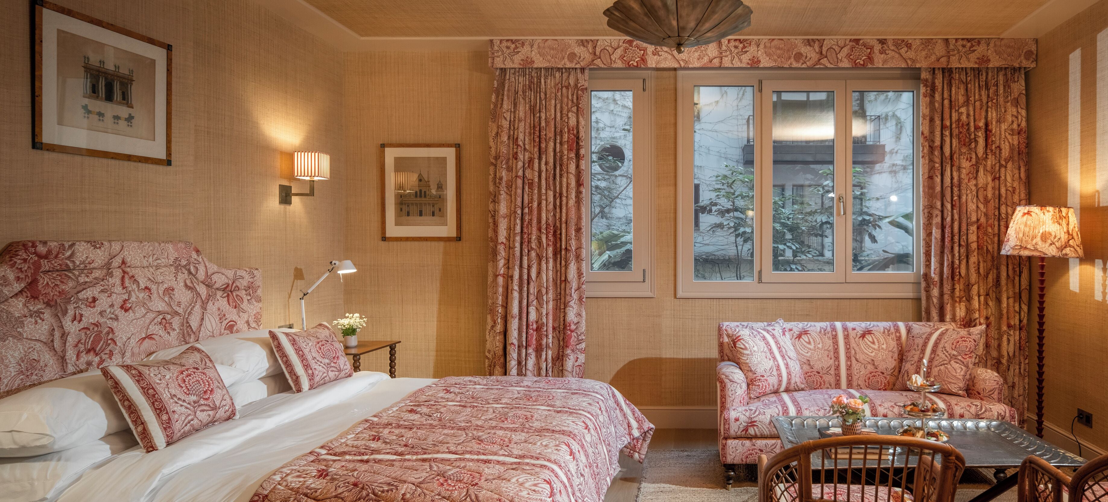A bedroom with a large bed, two bedside tables, a chair, and a small table with a lamp.