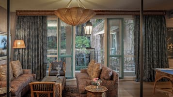 A cozy living room with patterned sofas, a dining table, and a view of a garden through large sliding doors.