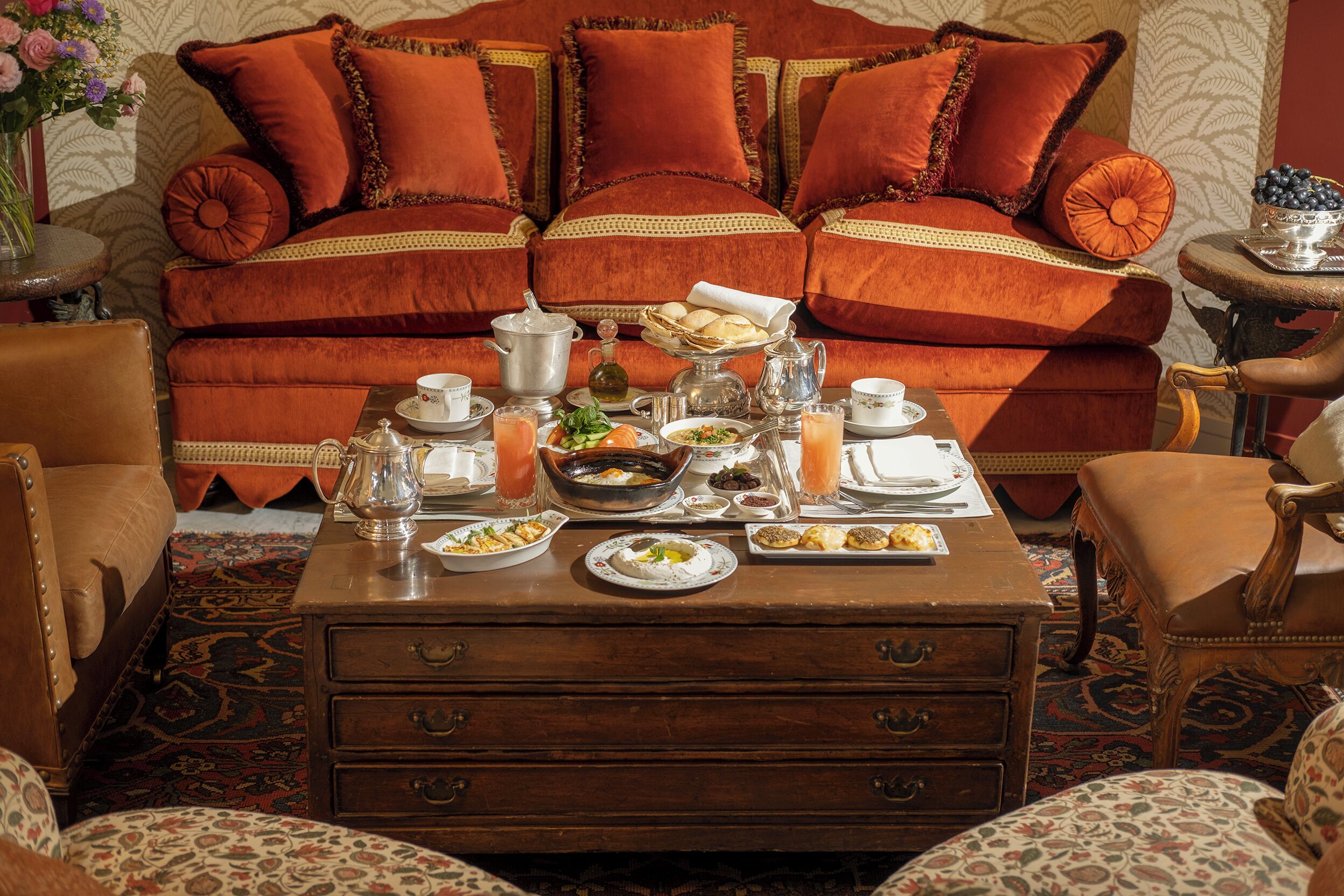 Un comedor con sofá, una mesa de centro con comida y bebidas, y una alfombra estampada.