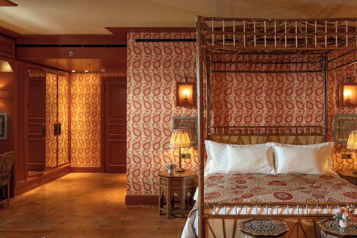 Un lit à baldaquin avec une couvre-lit à motifs, une tête de lit en bois et deux tables de chevet avec des lampes.