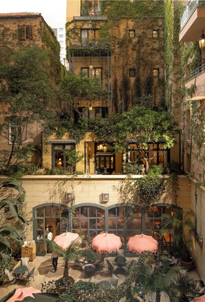 A courtyard with outdoor seating, surrounded by buildings with ivy-covered walls and multiple windows. - Hotel Albergo (Beirut)