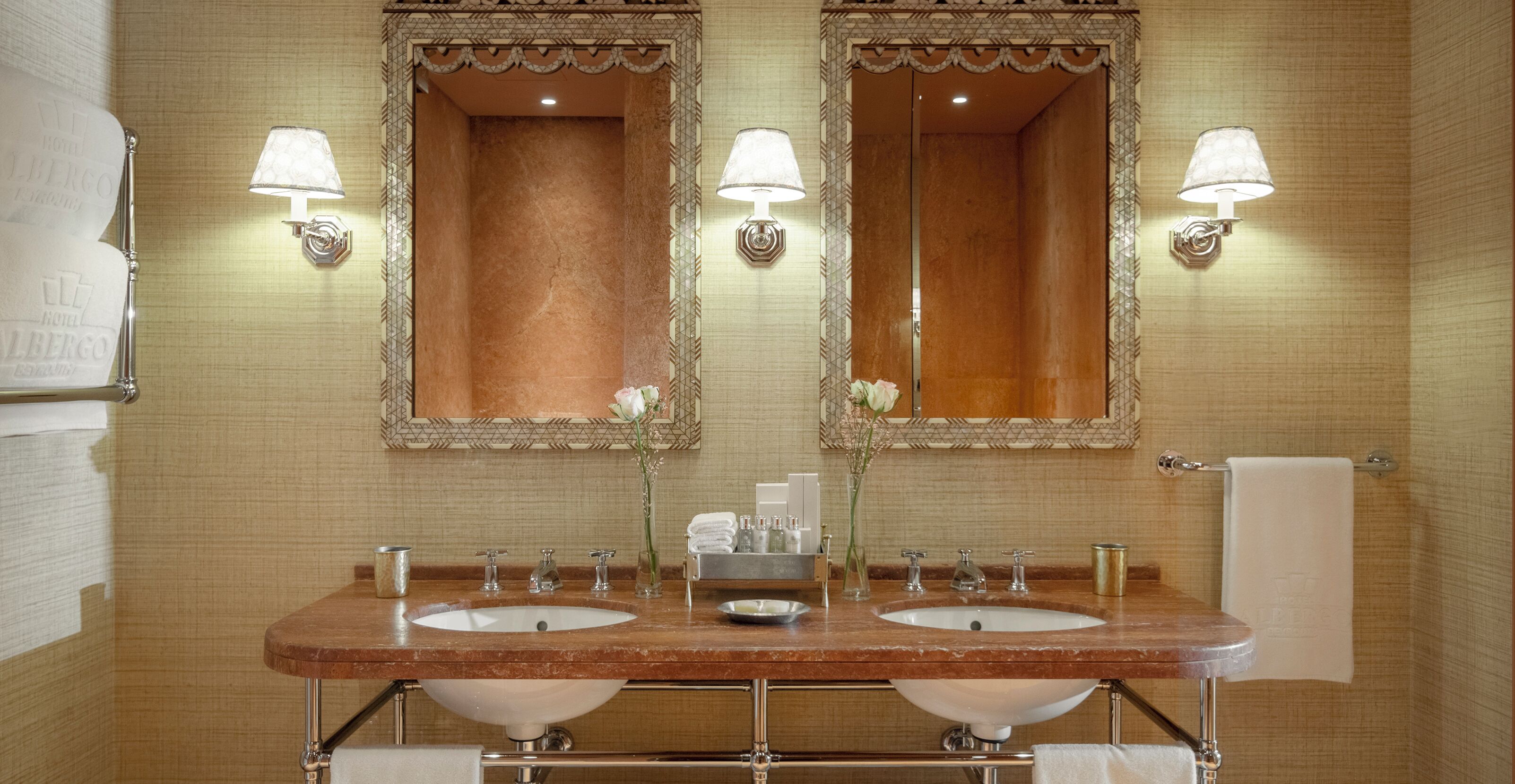 A bathroom with two sinks, two mirrors, and two wall-mounted lamps.