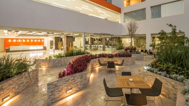 Un espace extérieur moderne, aménagé en terrasse, avec des murs en pierre, des sièges et un restaurant en arrière-plan.