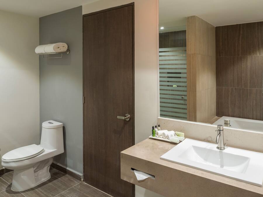 A modern bathroom with a toilet, sink, and mirror.
