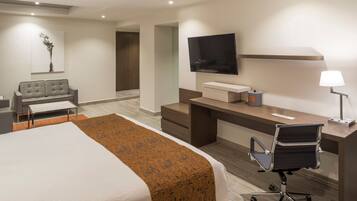 Een moderne hotelkamer met een bed, een bureau, een stoel, een televisie en een lamp.