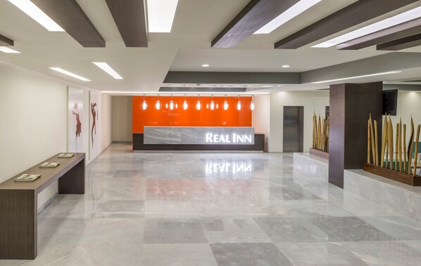 A spacious lobby with a reception desk, modern lighting, and a polished floor.