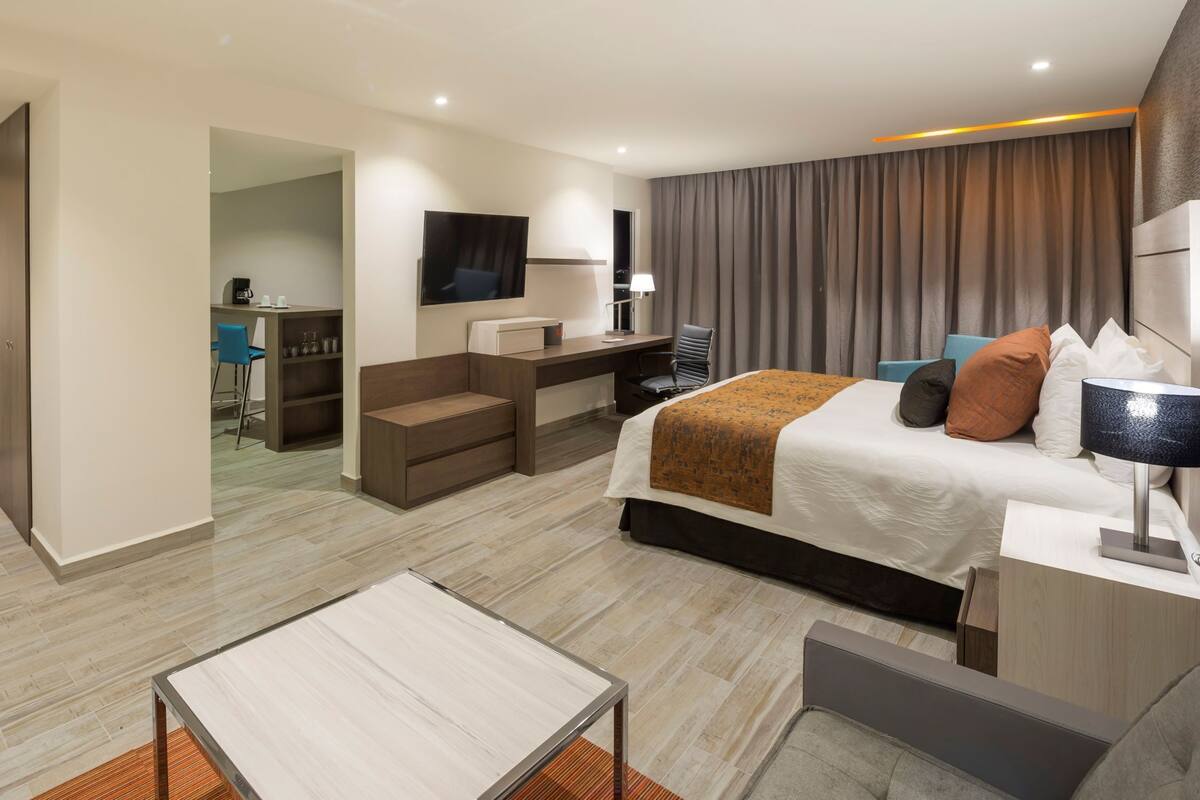 Une chambre d’hôtel moderne équipée d’un lit, d’un bureau et d’un coin salon.