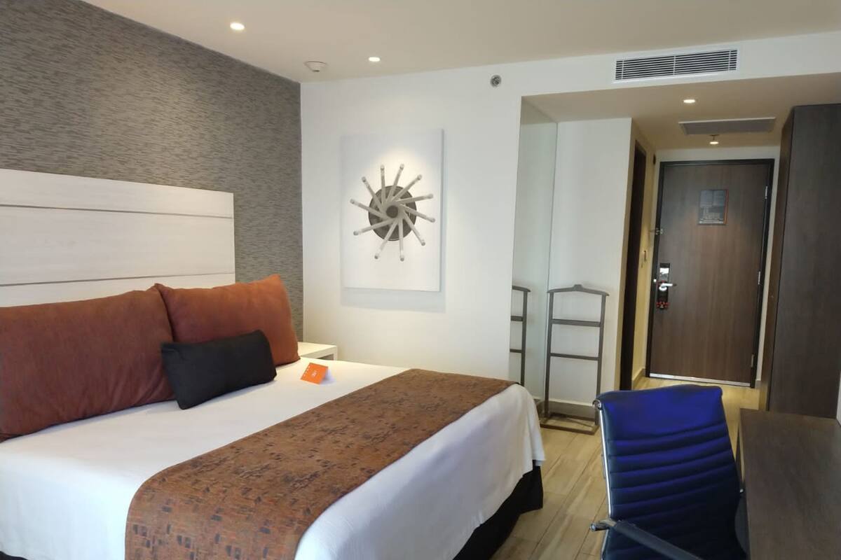 Une chambre d’hôtel avec un lit, un bureau et une chaise.