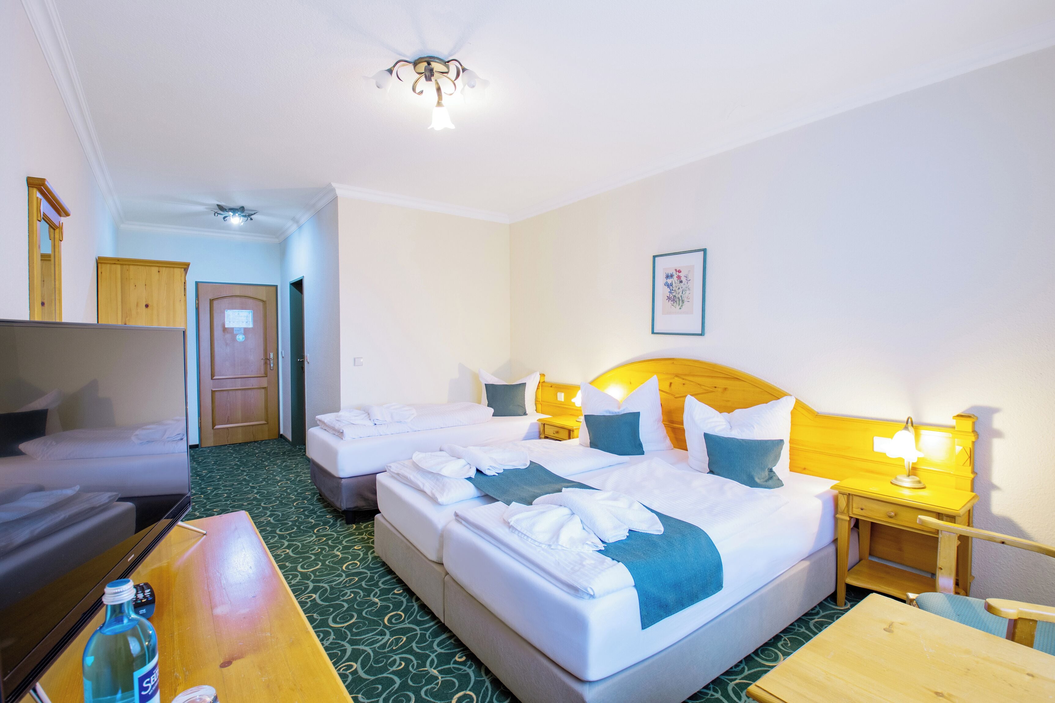 Ein Hotelzimmer mit zwei Betten, einem Schreibtisch, einem Stuhl, einem Fernseher und einer Badezimmertür.