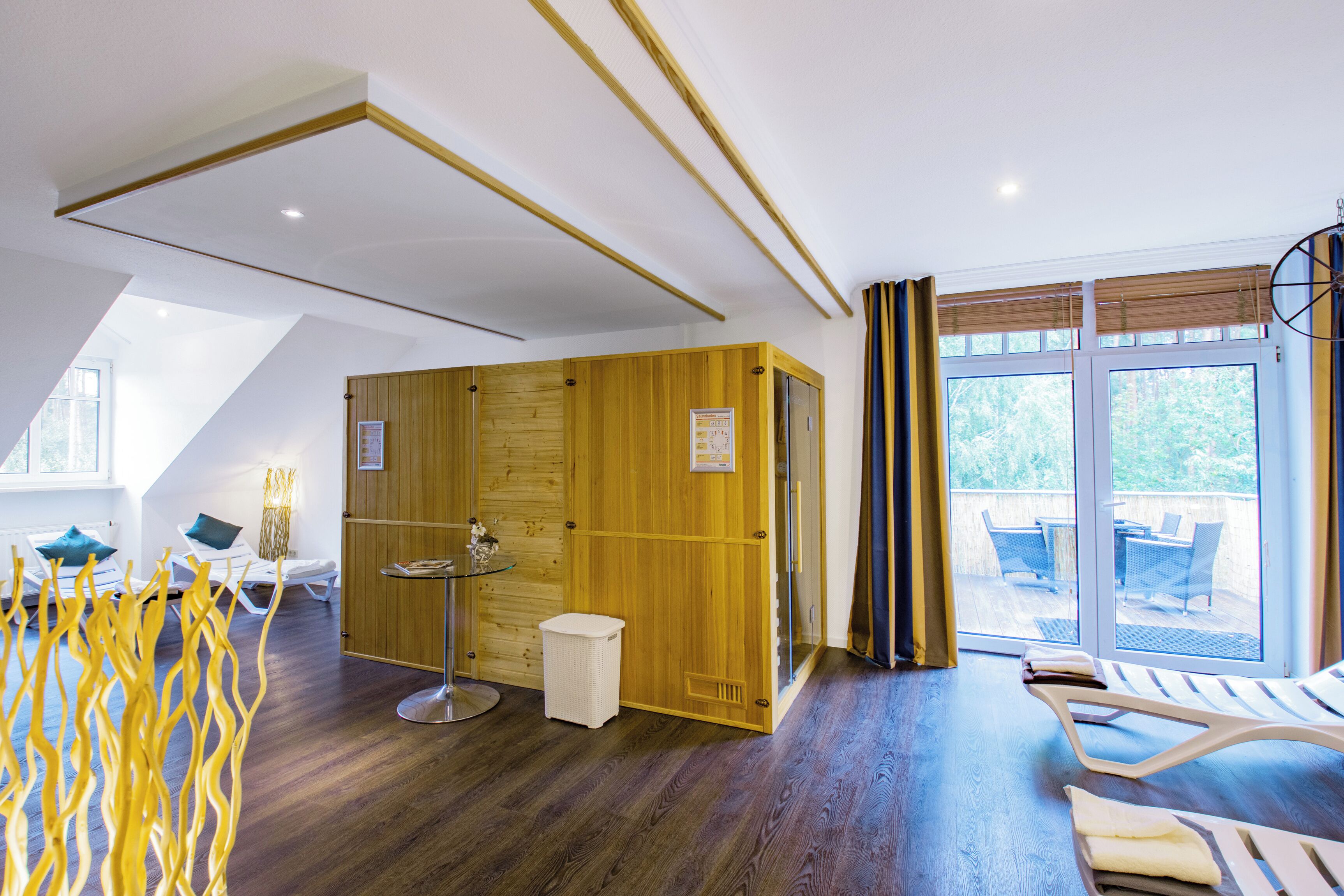 Ein modernes Zimmer mit Holzverkleidung, einer Glastür zu einem Außenbereich und einer Sitzecke mit Lounge-Stühlen.
