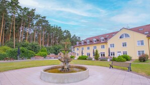 Ein Innenhof mit einem Brunnen, Bänken und einem Gebäude mit einem Ziegeldach.