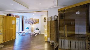 Ein geräumiger Raum mit Holzboden, einer Glastrennwand und Blick ins Freie. Zwei Lounge-Sessel mit Kissen sind vorhanden.