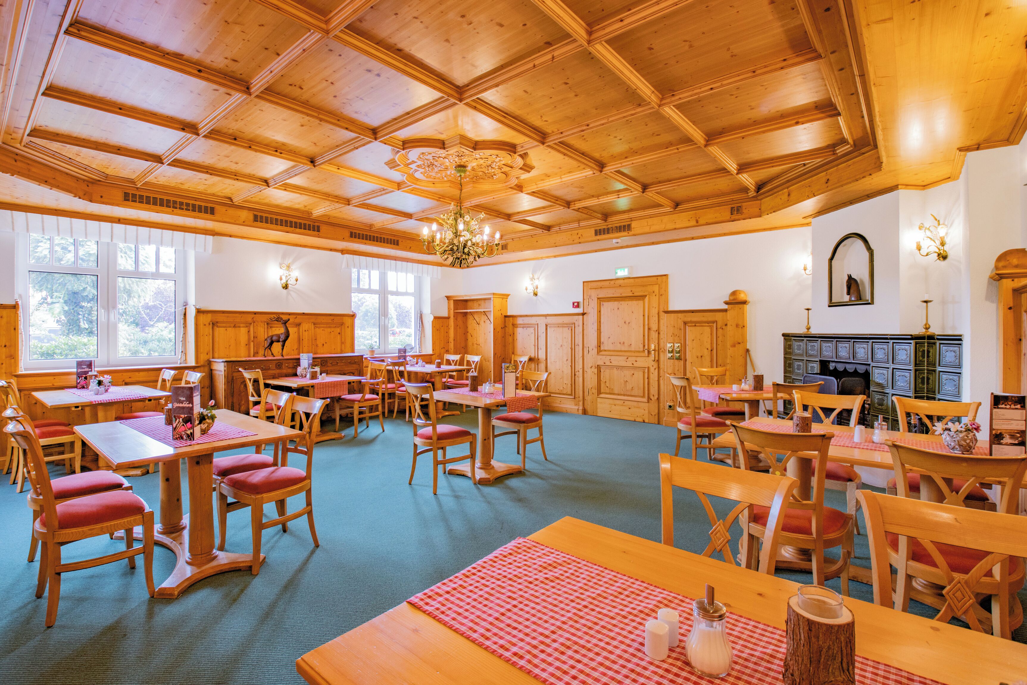 A spacious dining area with wooden tables and chairs, a chandelier, and a fireplace.