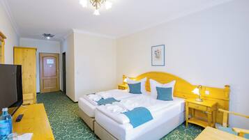 Een hotelkamer met een bed, nachtkastjes, een bureau, een televisie en een deur.