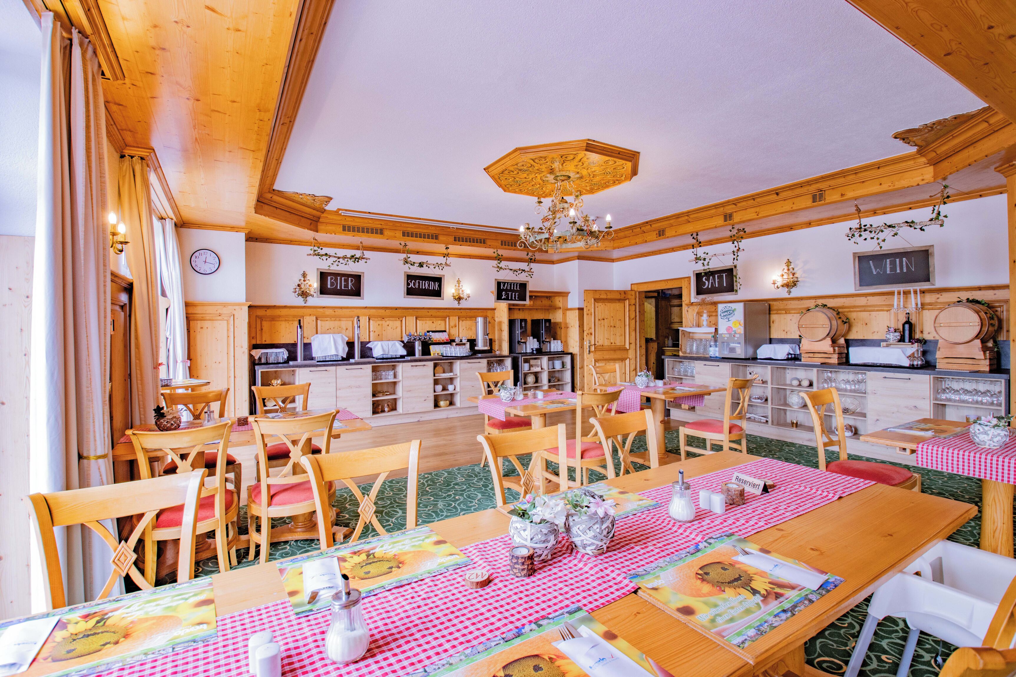 Een gezellig restaurant met houten inrichting, meerdere eettafels en diverse zithoeken.