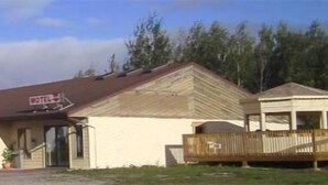 Un motel composé d’un bâtiment d’un seul étage, d’une véranda et d’un petit espace clôturé.