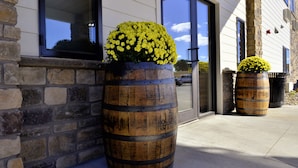 A building with stone and wooden elements, large windows, and two wooden barrels with yellow flowers.