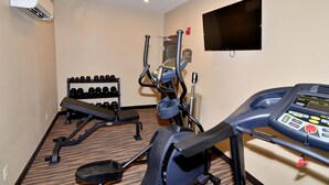A gym with a treadmill, elliptical, and dumbbells.