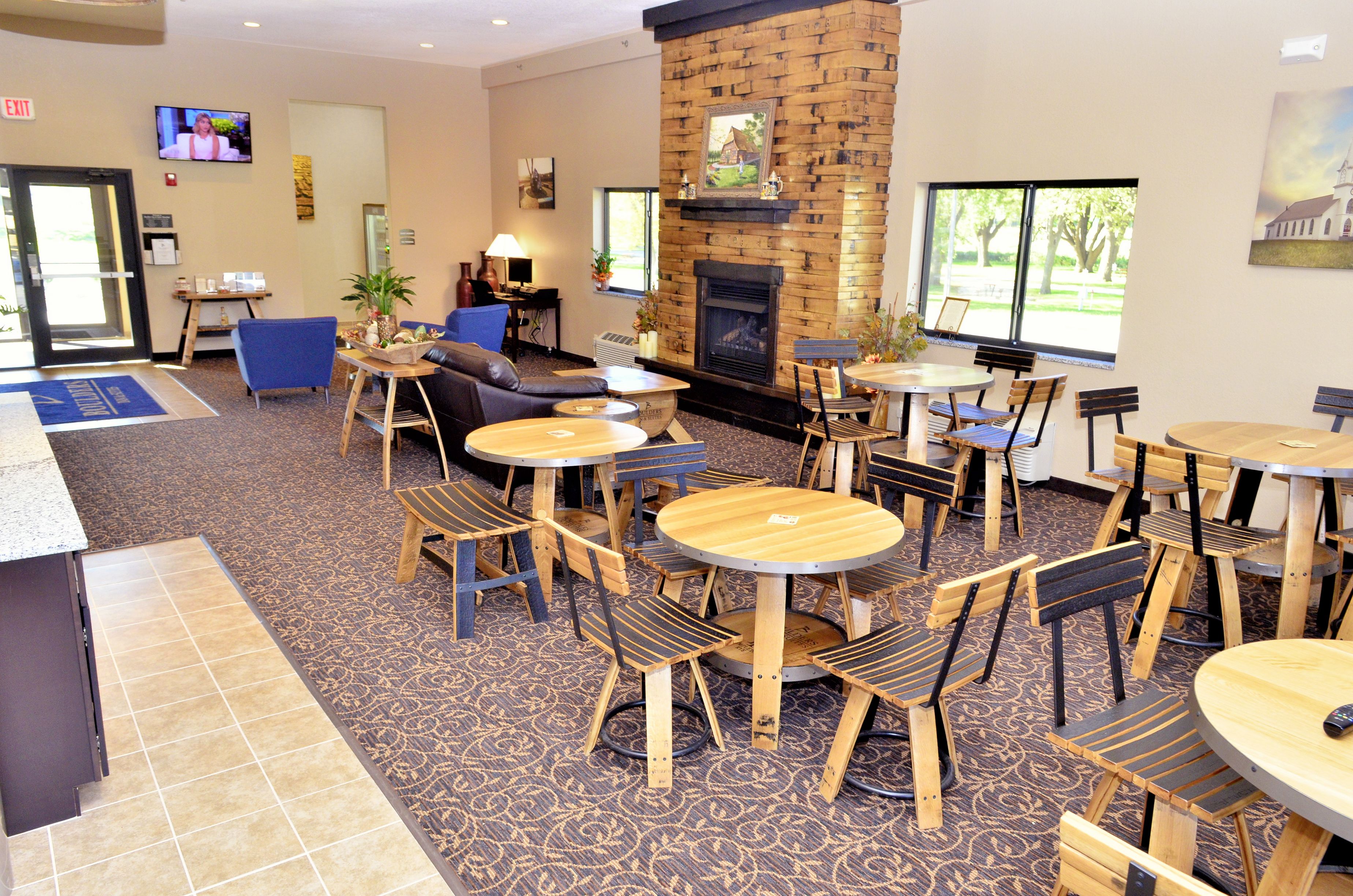 A hotel lobby with a fireplace, multiple seating areas, and a television on the wall.