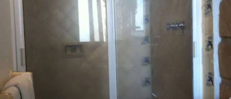 Un baño con cabina de ducha de vidrio, inodoro y lavabo.