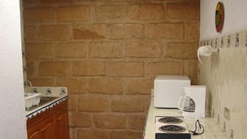 A kitchen with a brick wall, a white countertop, a stove, and a microwave.