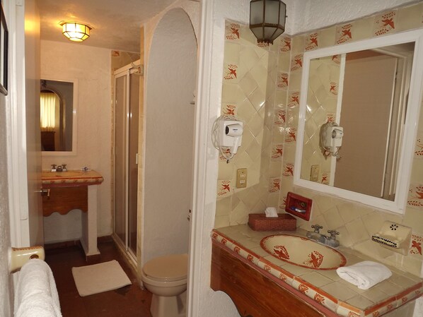 Un baño con ducha, inodoro, lavamanos y espejo.