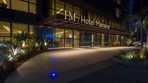 Exterior de l'Hotel Manara, amb façana moderna, grans finestres de vidre i una zona d'entrada ben il·luminada.